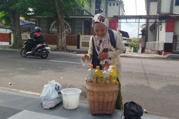 Parmi melayani pembeli jamu dengan cekatan di area Taman Blambangan Banyuwangi, Jumat, (10/1/2025). 