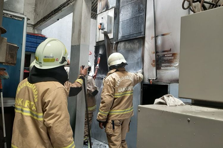 Petugas melakukan upaya pendinginan pada mesin oven yang sebelumnya terbakar di di bengkel mobil di Jalan Hadiah, Jelambar, Grogol Petamburan, Jakarta Barat, terbakar pada Sabtu (1/10/2022). 