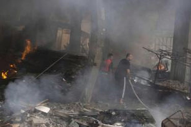 Warga Palestina berusaha memadamkan api setelah sebuah roket milik militer Israel menghantam gedung di kota Gaza, 10 Juli 2014. Militer Israel meluncurkan roket dan menyerang lebih dari 300 target untuk melawan Hamas di jalur Gaza.