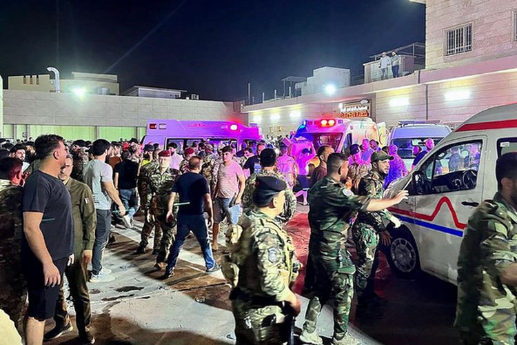 Tentara dan petugas tanggap darurat berkumpul di sekitar ambulans yang membawa orang-orang yang terluka setelah kebakaran pesta pernikahan di Irak, di luar rumah sakit umum Al-Hamdaniyah di Bakhdida, Irak pada 27 September 2023. Sedikitnya 100 orang dilaporkan tewas dan lebih dari 150 orang lainnya terluka dalam insiden kebakaran pesta pernikahan di Irak tersebut,