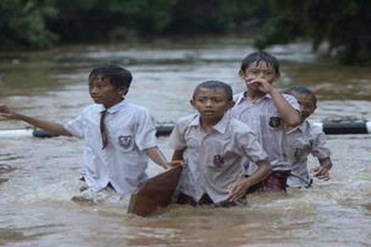 Dengan masih mengenakan seragam sekolah, siswa bermain di air banjir yang menggenangi Jalan Bukit Duri Utara Raya, Jakarta Selatan, Rabu (16/1/2013).   
