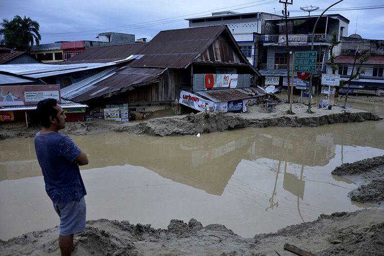 Warga memerhatikan rumah yang tertimbun lumpur akibat terjangan banjir bandang di Kecamatan Masammba, Kabupaten Luwu Utara, Sulawesi Selatan, Rabu (15/7/2020). Banjir bandang yang terjadi akibat tingginya curah hujan tersebut mengakibatkan 16 orang meninggal dunia dan puluhan warga dilaporkan masih dalam pencarian, sementara ratusan rumah rusak berat dan hilang.