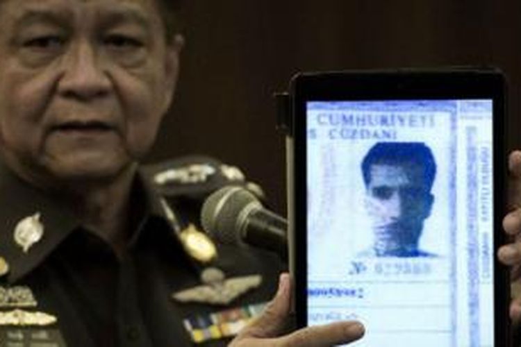 Polisi Thailand, Prawut Thavornsiri, memegang foto warga asing yang diduga pelaku pemboman. 