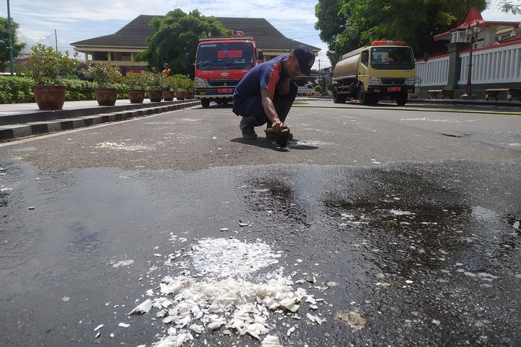 Petugas Damkar membersihkan sisa lilin acara doa bersama suporter yang menemp di aspal jalan depan Kantor Bupati Banyumas, Jawa Tengah, Selasa (4/10/2022).