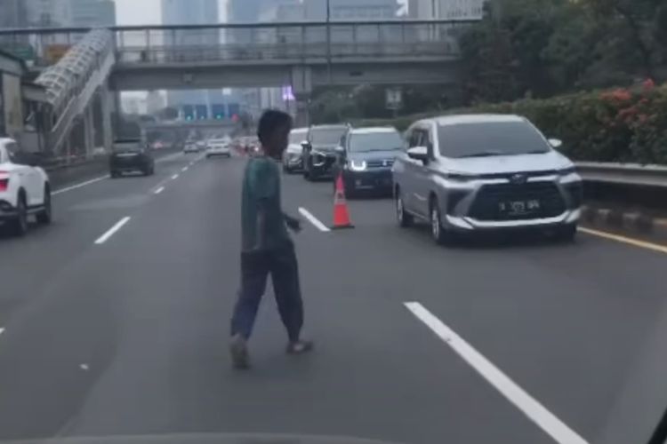 Seorang pria berjalan di tengah jalan tol dalam kota Semanggi mengarah Kuningan, Jakarta pada Rabu (13/7/2022) pagi.