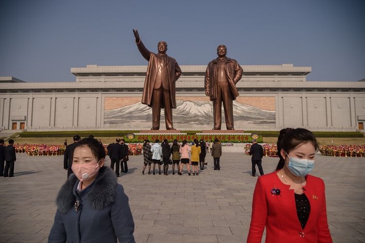 Orang-orang yang memakai topeng wajah pergi setelah meletakkan bunga di depan patung-patung pemimpin Korea Utara Kim Il Sung dan Kim Jong Il pada kesempatan ulang tahun ke-108 dari pemimpin Korea Utara Kim Il Sung, yang dikenal sebagai Day of the Sun, di Pyongyang pada 15 April 2020.
