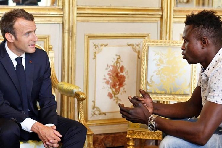 Presiden Perancis Emmanuel Macron berbincang dengan Mamoudou Gassama di Istana Elysee Senin (28/5/2018). Gassama menuai pujian setelah memanjat gedung demi menyelamatkan seorang bocah Sabtu (26/5/2018).