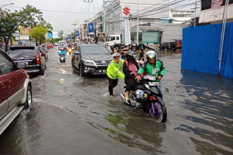 Polisi lalu lintas di pekanbaru membantu warga saat motornya mogok akibat genangan banjir