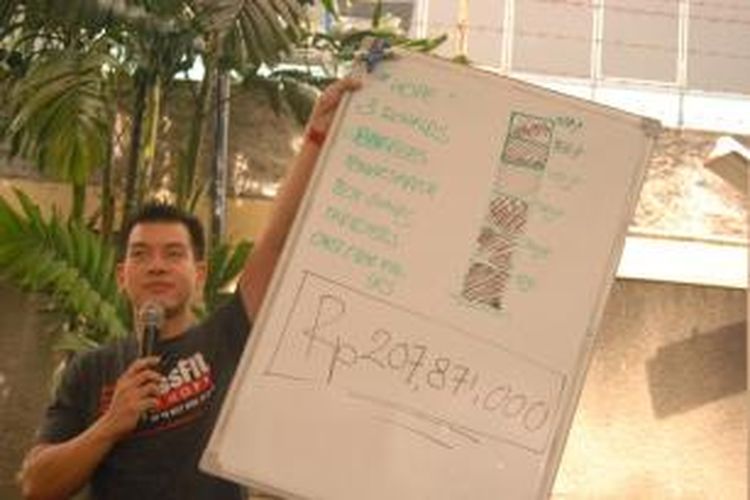 Kepala pelatih Crossfit Equator, Pandji Brian, menunjukkan total donasi yang diperoleh dari acara Crossfit for Hope di Hotel Garden, Kemang, Sabtu (6/7/2013).