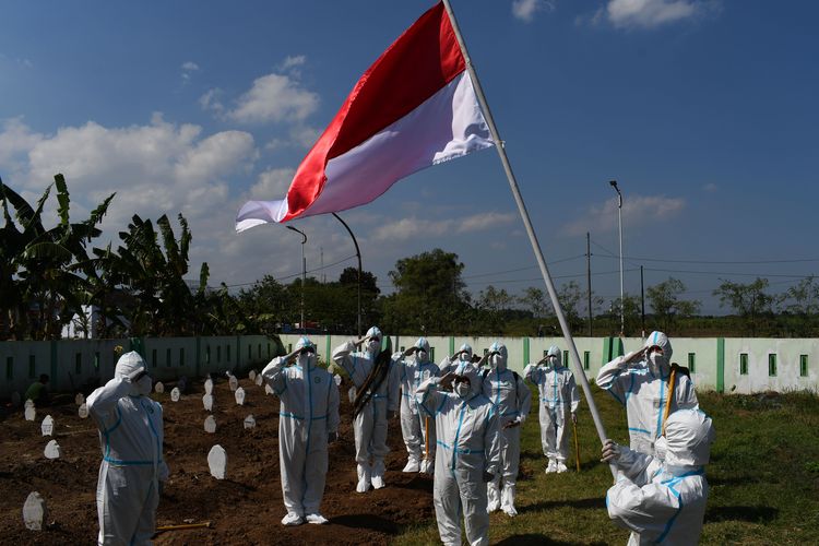 Sejumlah relawan pemakaman jenazah protokol COVID-19 dengan mengenakan Alat Pelindung Diri (APD) melakukan upacara bendera dalam rangka peringatan Hari Ulang Tahun ke-76 Proklamasi Kemerdekaan RI di Pemakaman Pagu Indah Kota Madiun, Jawa Timur, Minggu (15/8/2021). Para relawan pemakaman jenazah tersebut terdiri dari unsur Palang Merah Indonesia (PMI), Badan Penanggulangan Bencana Daerah (BPBD) dan Puskesmas. ANTARA FOTO/Siswowidodo/foc.