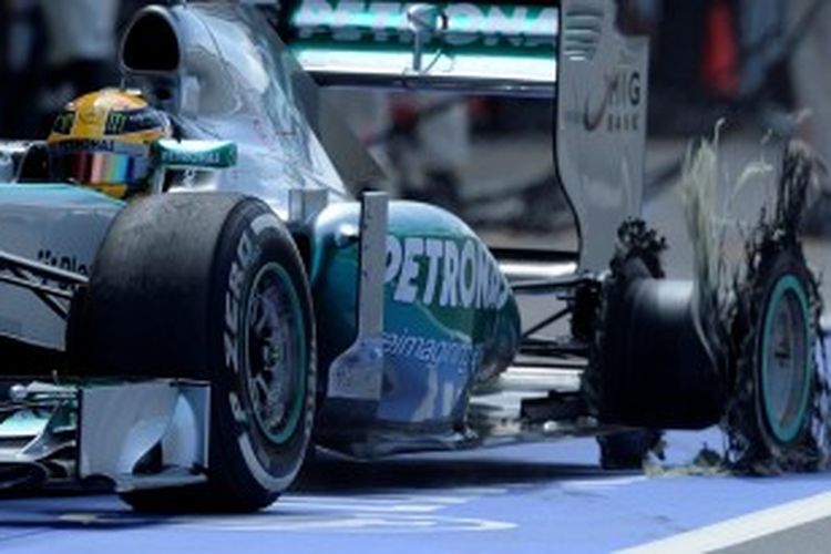 Pebalap Mercedes, Lewis Hamilton, masuk ke pit dengan ban kiri belakang rusak, pada balapan GP Inggris di Sirkuit Silverstone, Minggu (30/6/2013).