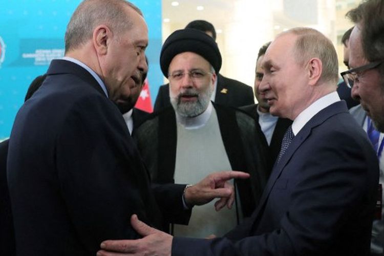 Gambar selebaran ini diambil dan dirilis oleh Kepresidenan Turkiye pada 19 Juli 2022 menunjukkan Presiden Turkiye Recep Tayyip Erdogan (kiri) berbicara dengan Presiden Rusia Vladimir Putin (kanan) saat Presiden Iran Ebrahim Raisi mendengarkan, saat mereka tiba untuk konferensi pers bersama di akhir KTT Trilateral Astana di Balai Konferensi Internasional Teheran di Teheran. Erdogan pada Senin (21/11/2022) mengancam akan meluncurkan operasi darat ke Suriah.