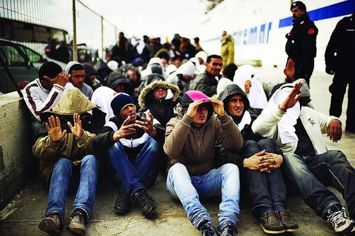 Imigran Tunisia yang mendarat di Pulau Lampedusa dalam beberapa hari terakhir menunggu untuk dinaikkan ke perahu yang akan membawa mereka ke pusat penampungan, Senin (14/2). Lebih dari 5.000 pencari suaka asal Tunisia yang mendarat di Lampedusa, menyusul kerusuhan yang terjadi di negara Afrika Utara itu, ditampung di pusat penampungan yang kembali dibuka. Organisasi Migrasi Internasional mengatakan, sejak malam itu tidak terlihat lagi perahu pengungsi yang mendarat di Lampedusa.