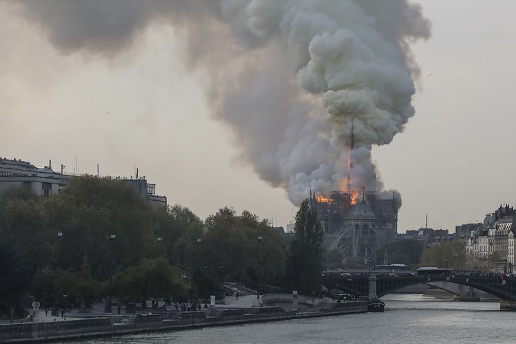 Api membakar bagian atas Gereja Notre Dame di Paris, Perancis, pada Senin (15/4/2019). Belum diketahui penyebab pasti kebakaran itu, api dengan cepat melalap atap dan puncak menara gereja bernuansa Gotik yang dibangun pada abad ke-12 itu.