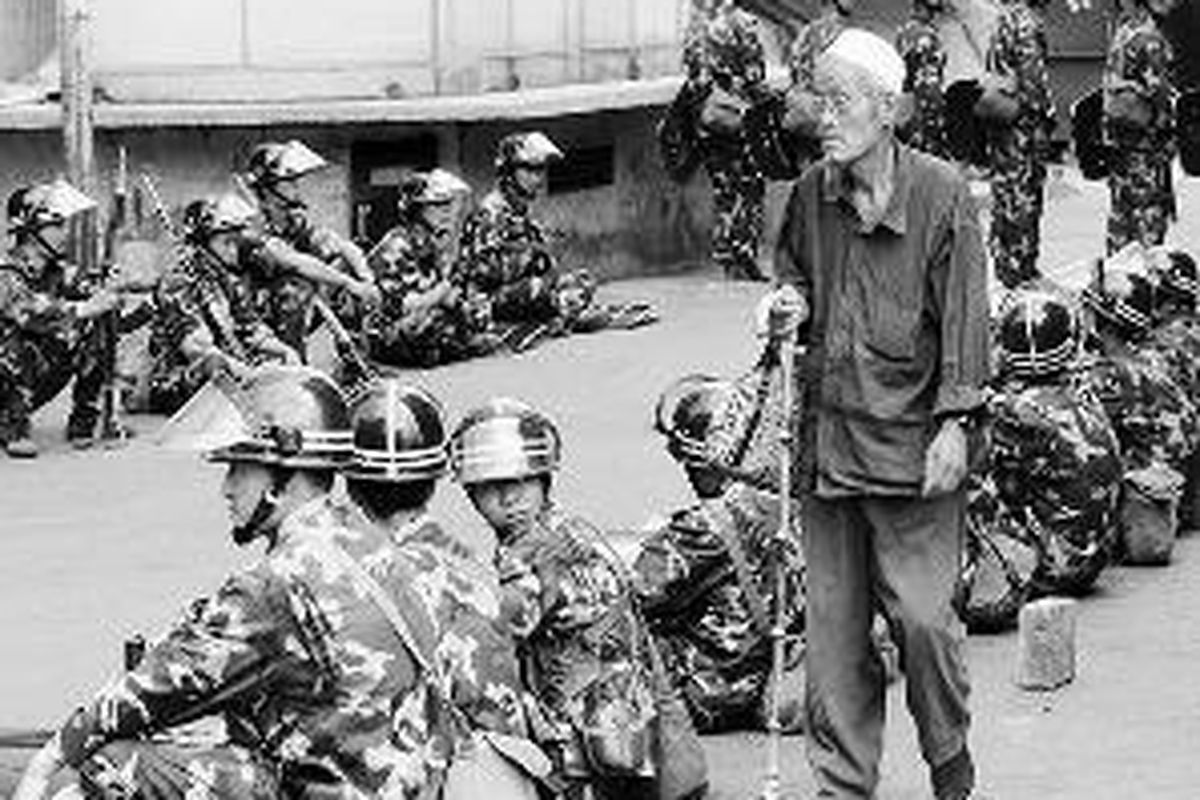 Seorang lelaki Muslim berjalan melewati deretan tentara China yang beristirahat di pinggiran jalan di Urumqi, ibu kota daerah otonomi khusus Xinjiang, China barat, Kamis (9/7). Pertikaian antara etnis minoritas Uighur dan warga mayoritas Han membuat aparat keamanan China menjaga ketat kota kaum Han dan Uighur ini. 