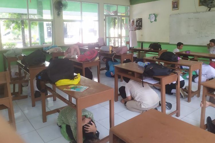 Siswa melakukan simulasi gempa di sekolah. 