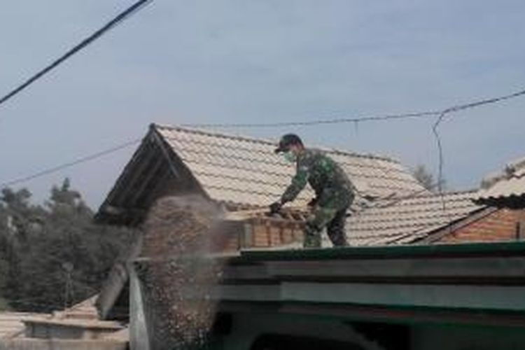Anggota TNI dari Batalyon Infantri 521 membersihkan pasir dan kerikil erupsi Gunung Kelud dari atas atap rumah warga di Desa Sugih Waras, Kecamatan Wates, Kabupaten Kediri, Jawa Timur, Sabtu (15/2/2014).
