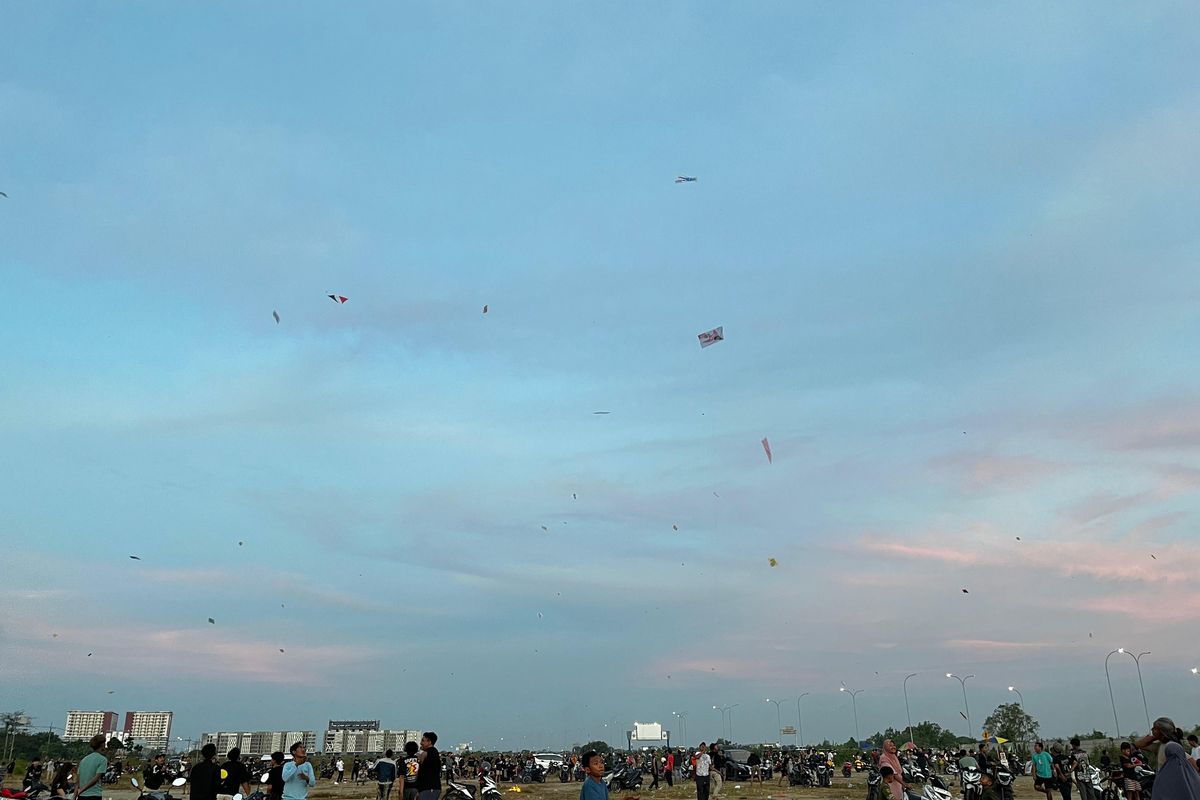 Suasana masyarakat mulai dari anak-anak, remaja, hingga orang tua yang bermain layangan di tanah lapang area sekitar Pondok Candra, Kecamatan Waru, Sidoarjo pada Kamis (17/7/2025).