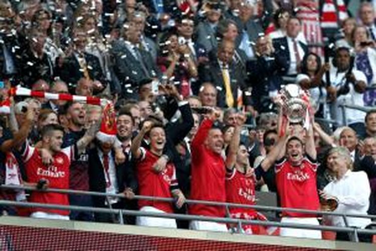 Para pemain Arsenal saat menerima trofi Piala FA seusai menaklukkan Hull City 3-2 pada partai final Piala FA di Stadion Wembley, Sabtu (17/5/2014). 