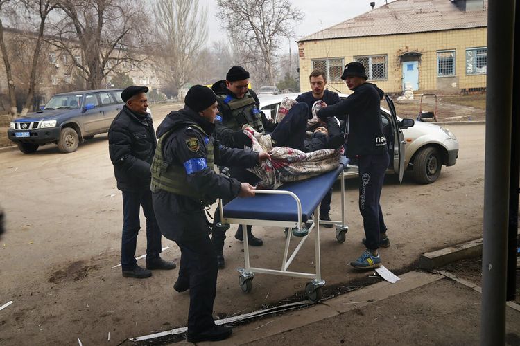 Prajurit dan sukarelawan Ukraina membawa seorang pria yang terluka dalam serangan penembakan ke rumah sakit nomor 3 di Mariupol, Ukraina, Selasa, 15 Maret 2022. (AP Photo/Evgeniy Maloletka)
