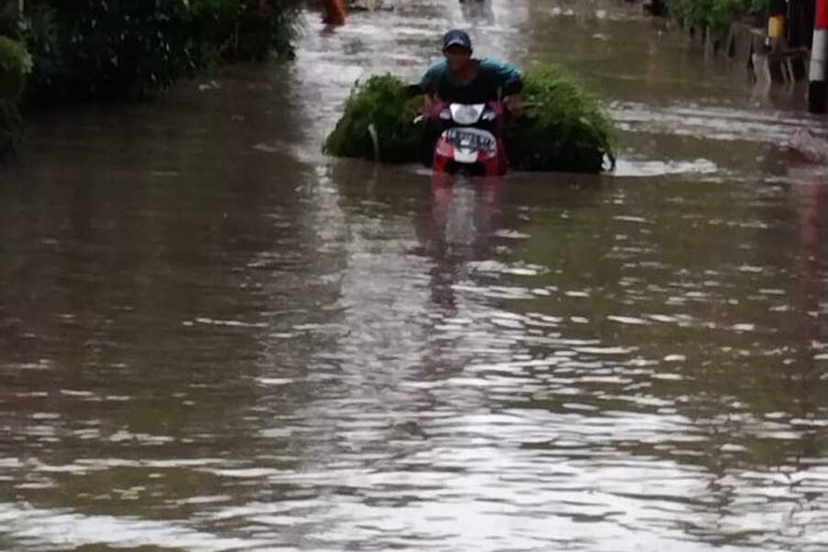 Warga mengendarai sepeda motor saat melintasi banjir di Sumberharjo, Kecamatan Prambanan, Kabupaten Sleman. Banjir disebabkan meluapnya Sungai Gawe setelah turun hujan lebat di wilayah Prambanan. (Foto Dokumentasi BPBD Sleman)