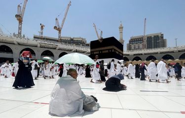 Seorang jamaah haji duduk sambil menaungi diri dengan payung di Masjidil Haram dalam Haji pertama setelah pemerintah Kerajaan Arab Saudi membuka kembali kegiatan Haji untuk warganegara asing yang ditutup akibat pandemi COVID-19 selama dua tahun di Mekah, Arab Saudi, Jumat (1/7/2022). (ANTARA FOTO/REUTERS/Mohammed Salem/wsj/NBL).