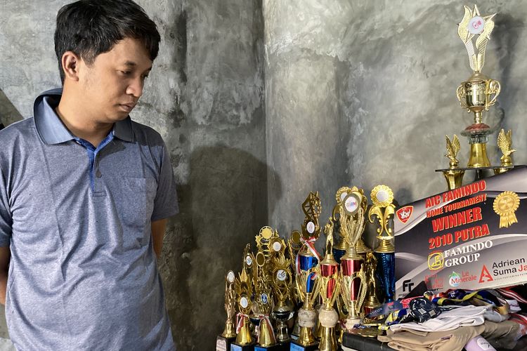 Hari, kakak pertama Ainun Al Munawar atlet muda bulu tangkis Indramayu saat menunjukkan tumpukan trofi dan mendali yang diraih adiknya dari berbagai kejuaraan bulu tangkis di rumah duka di Desa Nunuk, Kecamatan Lelea, Indramayu, Kamis (23/10/2025). 