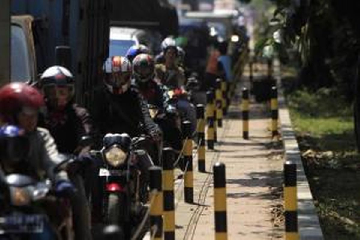 Pengguna sepeda motor tersendat di samping trotoar yang dipasangi tiang besi dan kawat baja di Jalan Raya Bekasi, Cakung, Jakarta Timur, Senin (16/4/2012). Tiang besi dan kawat baja dipasang untuk menutup jalan ke trotoar yang sering dipakai pengguna sepeda motor saat macet.