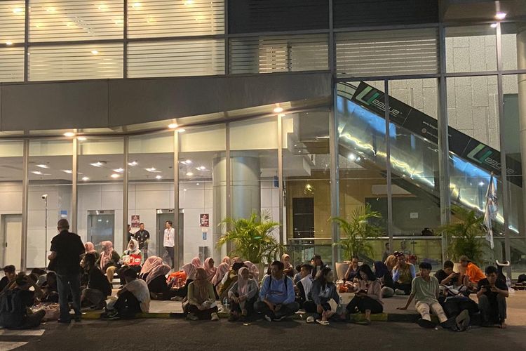 Pendukung Khofifah-Emil yang bersantai di luar gedung tanpa menonton live streaming debat ketiga Pilgub Jatim 2024, Senin malam (18/11/2024).