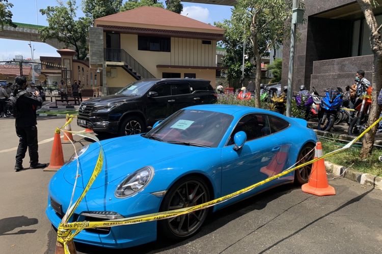 Mobil jenis Porsche 911 Carrera S berwarna biru milik tersangka Doni Salmanan yang disita polisi bakal menjadi barang bukti terkait kasus penipuan dan pencucian uang investasi ilegan binary option sang selebgram sudah digaris polisi di Bareskrim Polri, Senin (14/3/2022).