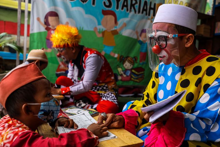 Yahya Edward Hendrawan, berkostum badut saat mengajar mengaji di Taman Baca Badut Syariah, Kawasan Pinang, Kota Tangerang, Jumat (30/4/2021). Yahya mengenakan kostum badut setiap mengajar baca-tulis Al-Quran sejak tahun 2010.