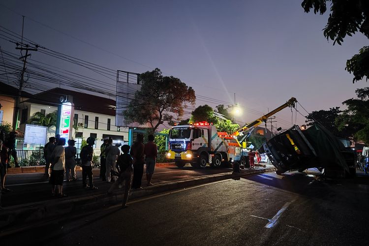 Proses evaluasi truk bermuatan 11 ton kardus yang terguling di depan Puskesmas Cimanggis, Jalan Raya Bogor, Curug, Kecamatan Cimanggis, Depok mulai berlangsung sejak pukul 18.20 WIB, Rabu (20/18/2023).