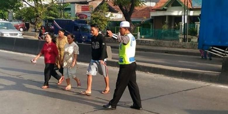 Seorang  santri anggota Satlantas Polres Demak, saat membantu warga menyeberang jalan, Jumat (10/6/2016)