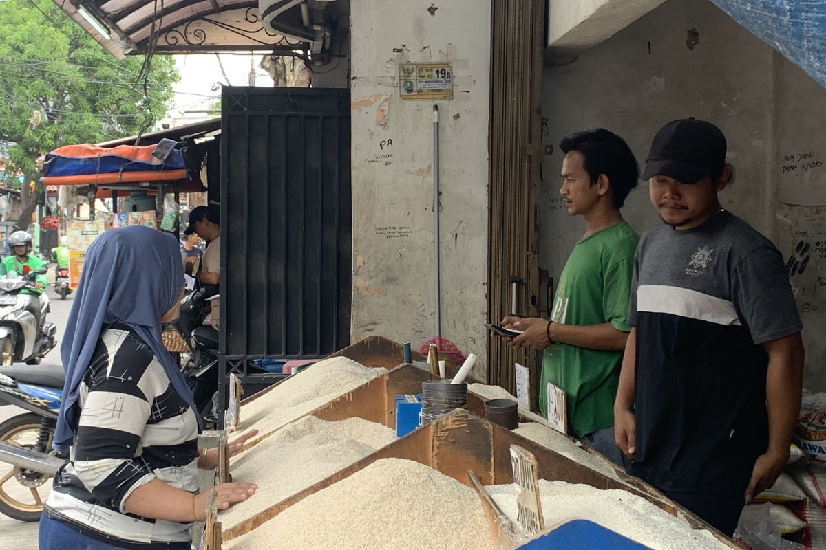 Penjual warteg, Ratna (50) saat membeli beras di kios Firdaus (24) di Jalan Rajawali, Kecamatan Bekasi Barat, Kota Bekasi, Rabu (21/2/2024).