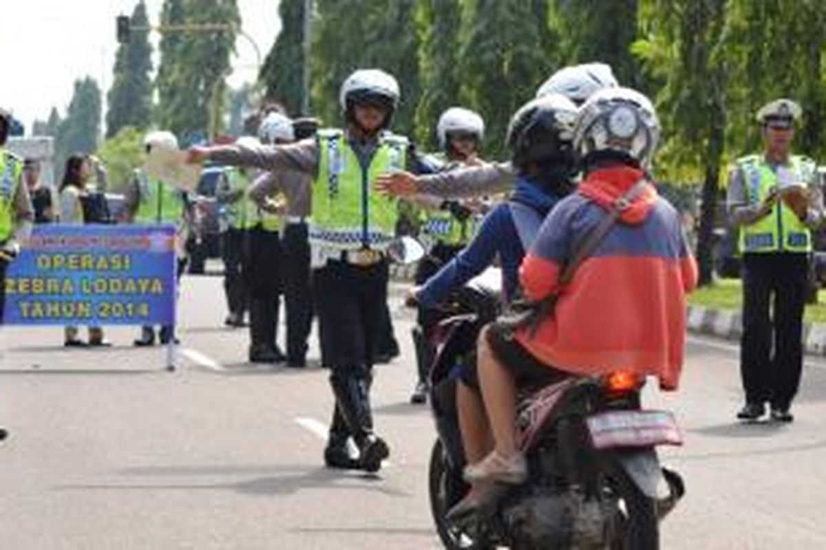 Salah satu petugas kepolisian dari Satuan Unit Lalulintas Polres Bogor, sedang memberhentikan pengendara sepeda motor dalam Operasi Zebra Lodaya 2014, Rabu (26/11/2014). K97-14