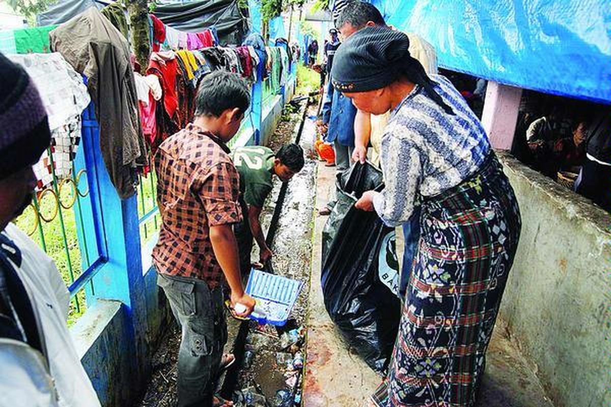Pengungsi di Jambur Taras, Berastagi, Tanah Karo, bekerja sama mengumpulkan sampah- sampah yang berserakan di lokasi pengungsian, Minggu (5/9). Selama di pengungsian, hubungan antarwarga semakin erat karena mereka merasa senasib.