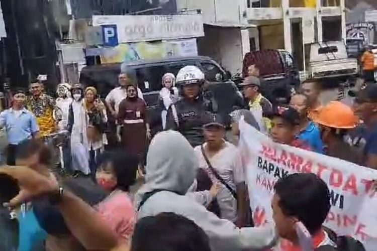 Warga membentangkan spanduk saat presiden RI Joko Widodo di depan Pasar Argosari, Wonosari, Gunungkidul. Selasa (30/1/2024)