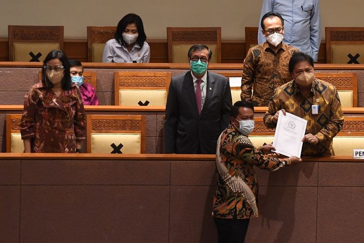 Menko Perekonomian Airlangga Hartarto (kanan) didampingi Menkumham Yasonna Laoly (kedua kiri) dan Menteri Keuangan Sri Mulyani (kiri) menerima laporan akhir dari Ketua Badan Legislasi DPR  Supratman Andi (bawah) saat pembahasan tingkat II RUU Cipta Kerja pada Rapat Paripurna DPR di Kompleks Parlemen, Jakarta, Senin (5/10/2020). ANTARA FOTO/Hafidz Mubarak A/pras.