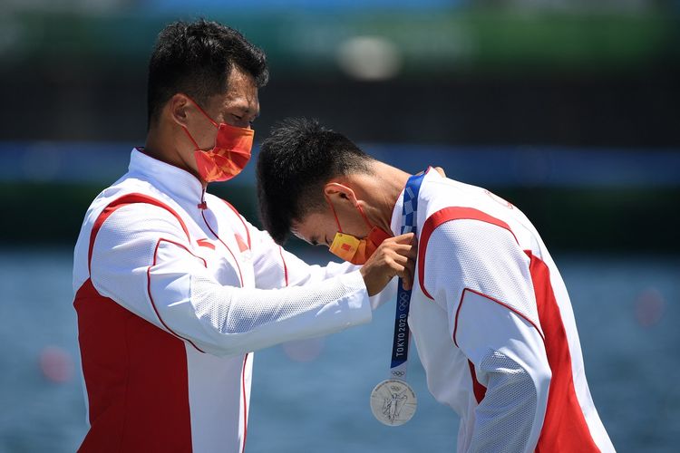 Atlet kano asal China, Zheng Pengfei (kiri) memberikan medali perak kepada rekan duetnya di nomor 1.000 meter kano ganda putra, Liu Hao, saat seromoni pengalungan medali Olimpiade Tokyo 2023 di Sea Forest Waterway, Tokyo, Jepang, 3 Agustus 2021.
