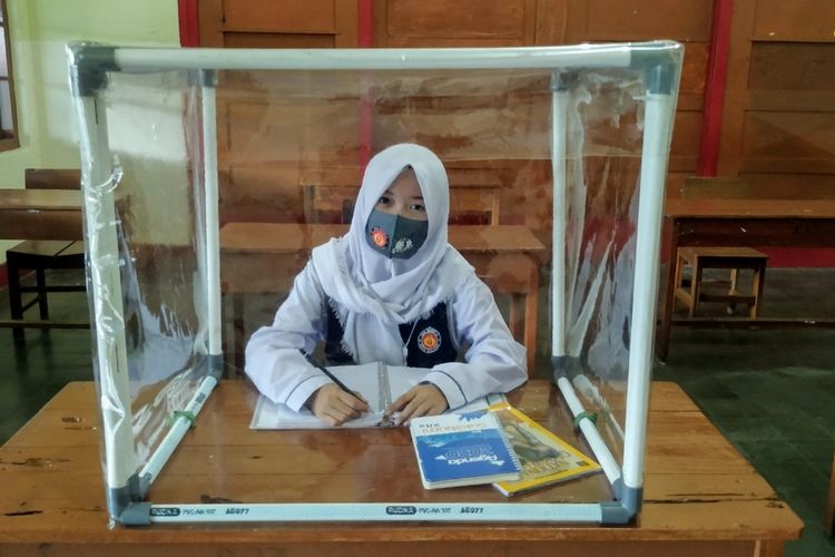 Seorang siswa mencoba duduk di meja belajar yang ditambahkan plastik di sekelilingnya di SMAN 4 Kota.Sukabumi, Jawa Barat, Rabu (8/7/2020).