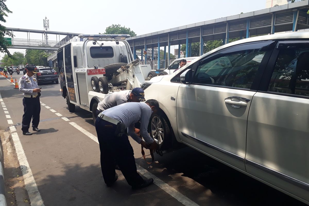 Petugas Suku Dinas Perhubungan Jakarta Timur saat menderek mobil yang parkir di bahu Jalan Pemuda, Jakarta Timur, Kamis (21/11/2019).