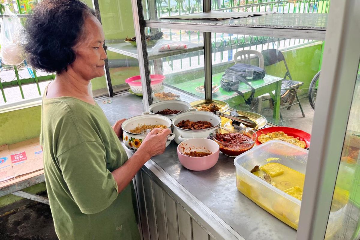 JUAL MAKAN—Pemilik warung Bu Min, Siti Nasiah sementara melayani warga yang memesan nasi bungkus di warungnya di Kartoharjo, Kota Madiun, Jawa Timur, Kamis (23/10/2025).