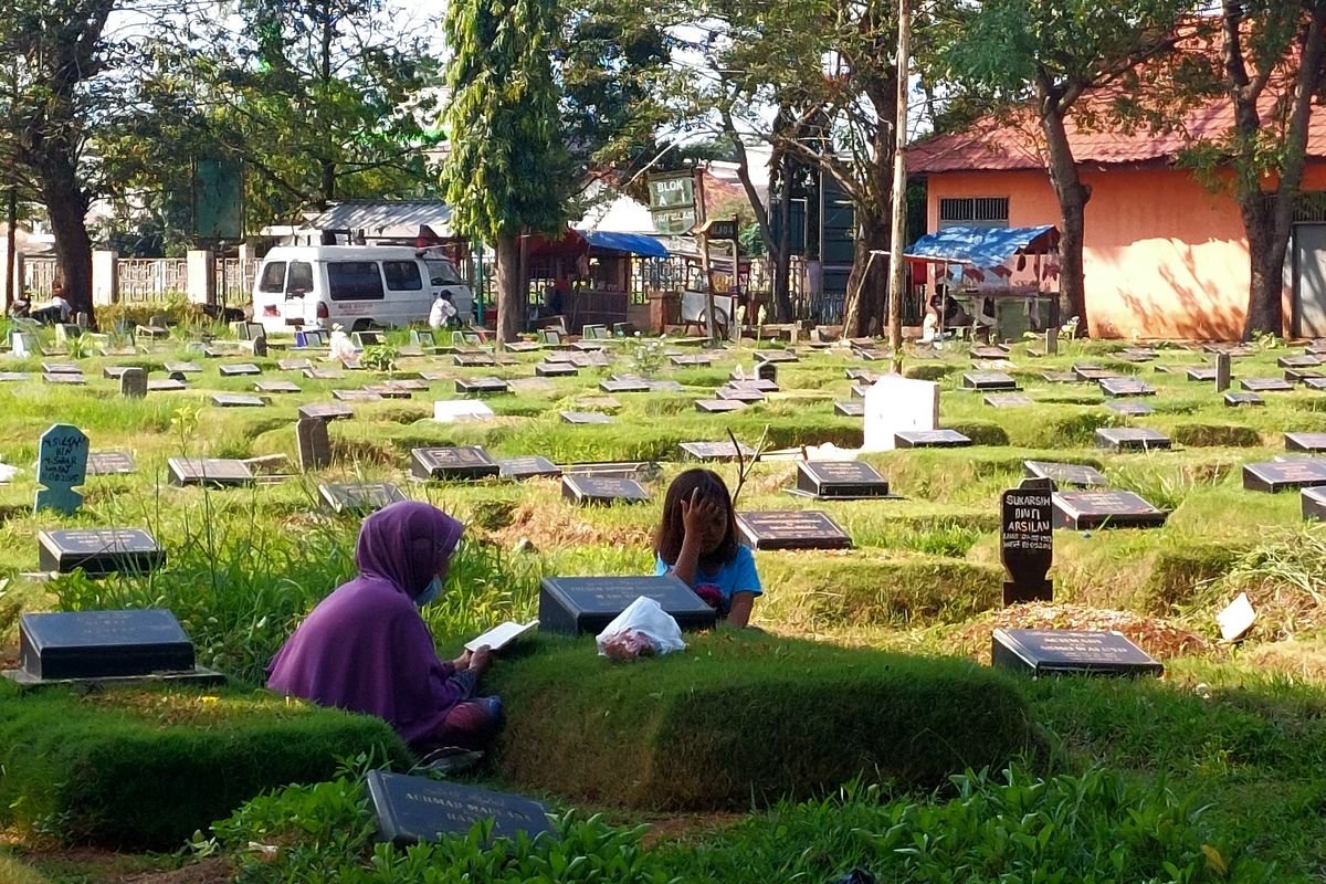 Sembari membacakan doa, seorang Ibu dan anak tengah berziarah di TPU Tegal Alur, Jakarta Barat, beberapa hari setelah lebaran, Kamis (5/5/2022).