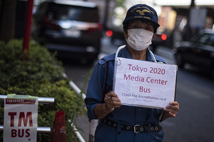 Petugas menunggu tibanya bus yang akan membawa peserta Olimpiade Tokyo 2020 di Shinjuku, Tokyo, Jepang, Rabu (21/7/2021). Para peserta Olimpiade Tokyo 2020 harus menggunakan bus atau transportasi khusus selama kegiatan olahraga tersebut berlangsung untuk menghindari kemungkinan tertularnya Covid-19.