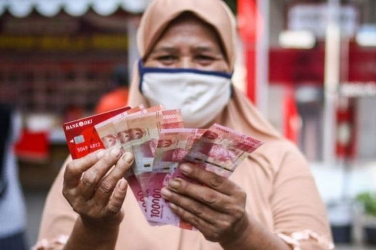 Warga menunjukkan uang bantuan sosial tunai atau BST usai mengambil di ATM Bank DKI, Jakarta, Selasa (20/7/2021).