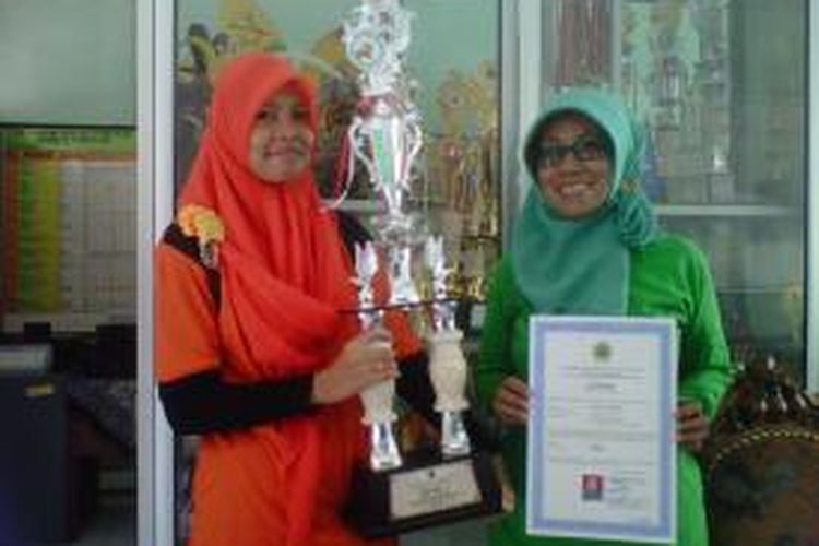 Fhila (kiri) membawa piala Juara I melukis tingkat Jawa Tengah dalam ajang FLS2N 2015.