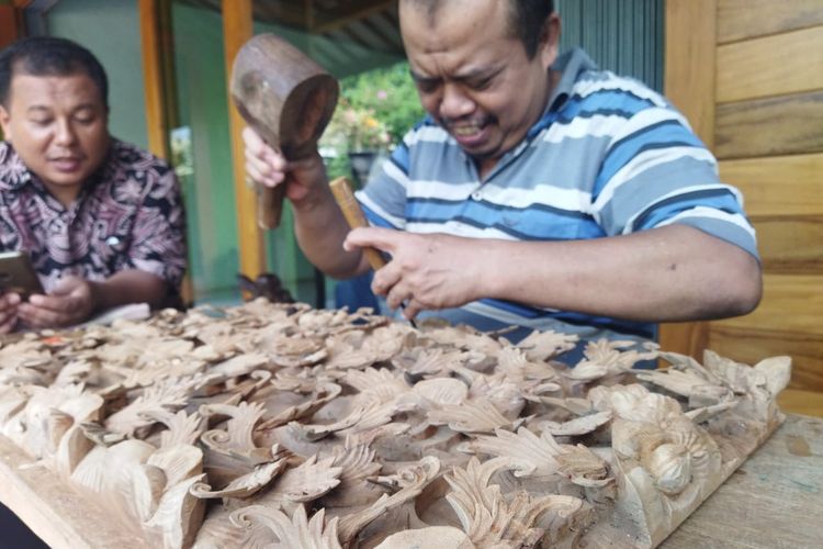 Seorang pengrajin seni ukir relief memahat kayu mahoni di salah sentra seni relief di Desa Senenan, Kecamatan Tahunan, Kabupaten Jepara, Jumat (1/7/2022).