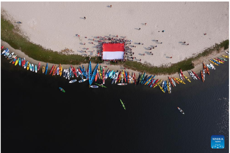 Tangkap layar foto pemberitaan Xinhua tentang pembentangan bendera di pantai Jakarta.