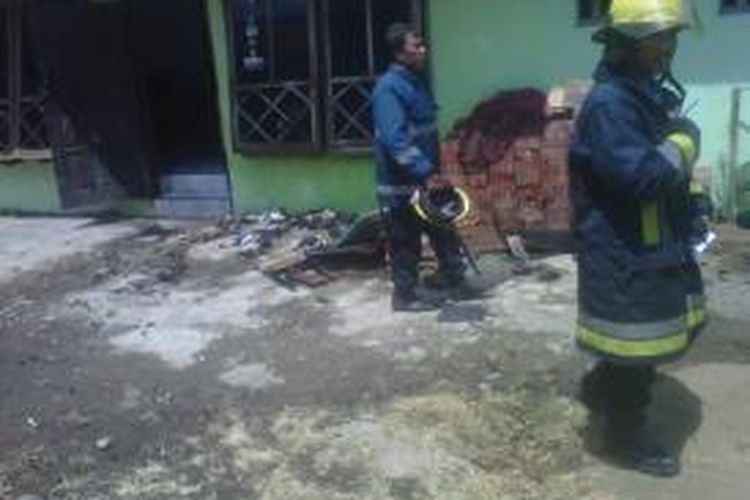 Dua petugas pemadam kebakaran melintas di depan rumah Hartiningsih warga Jl. Panglima Sudirman, Kota Kediri, Jawa Timur, yang sempat terbakar, Rabu (2/10/2013).
