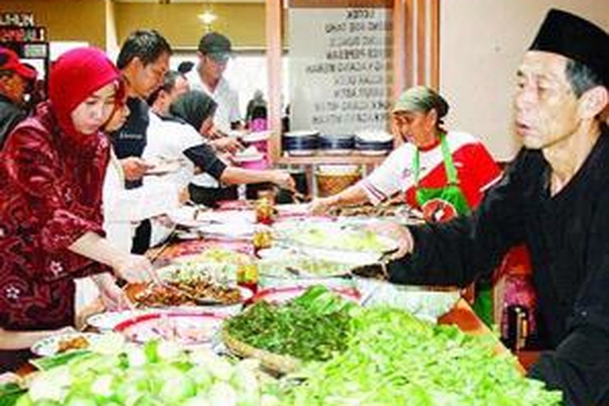 Pemilik Warung Nasi Bancakan di Bandung, Mang Obar dan Bi O'om, melayani pembeli. 